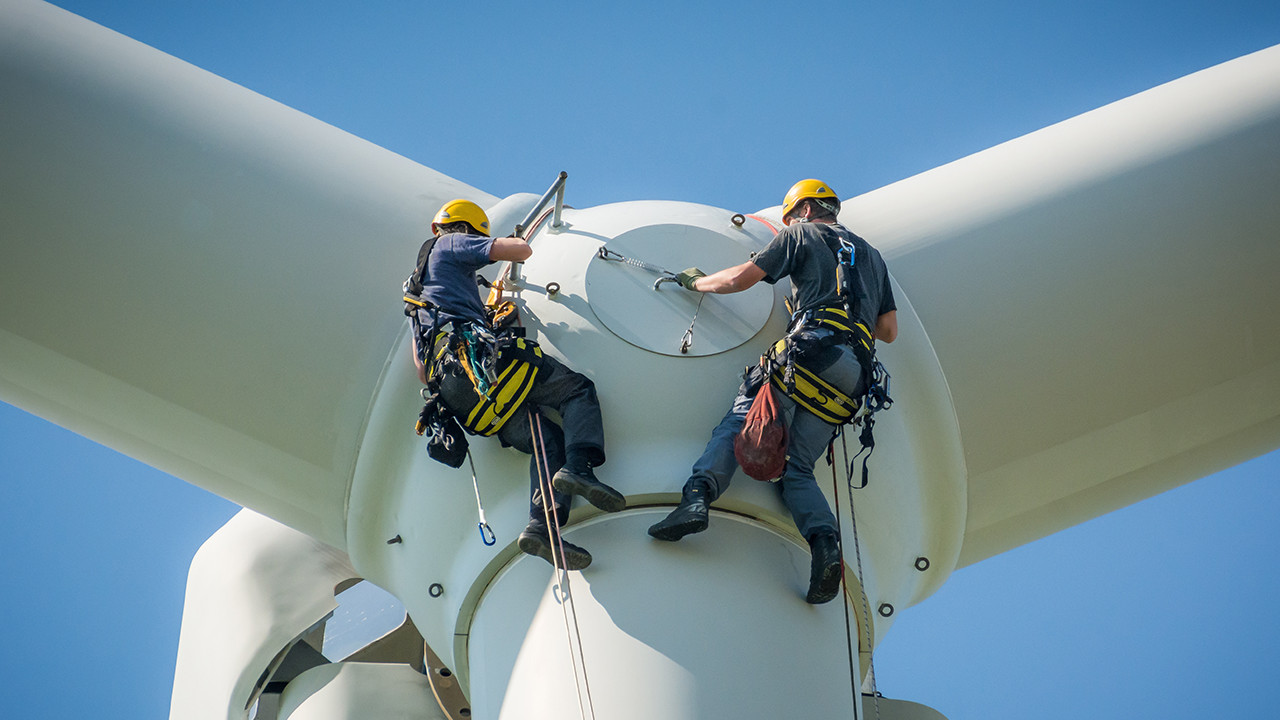 Monteure arbeiten am Rotor einer Windkraftanlage