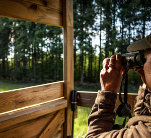 Jägerin mit Fernglas auf Hochsitz