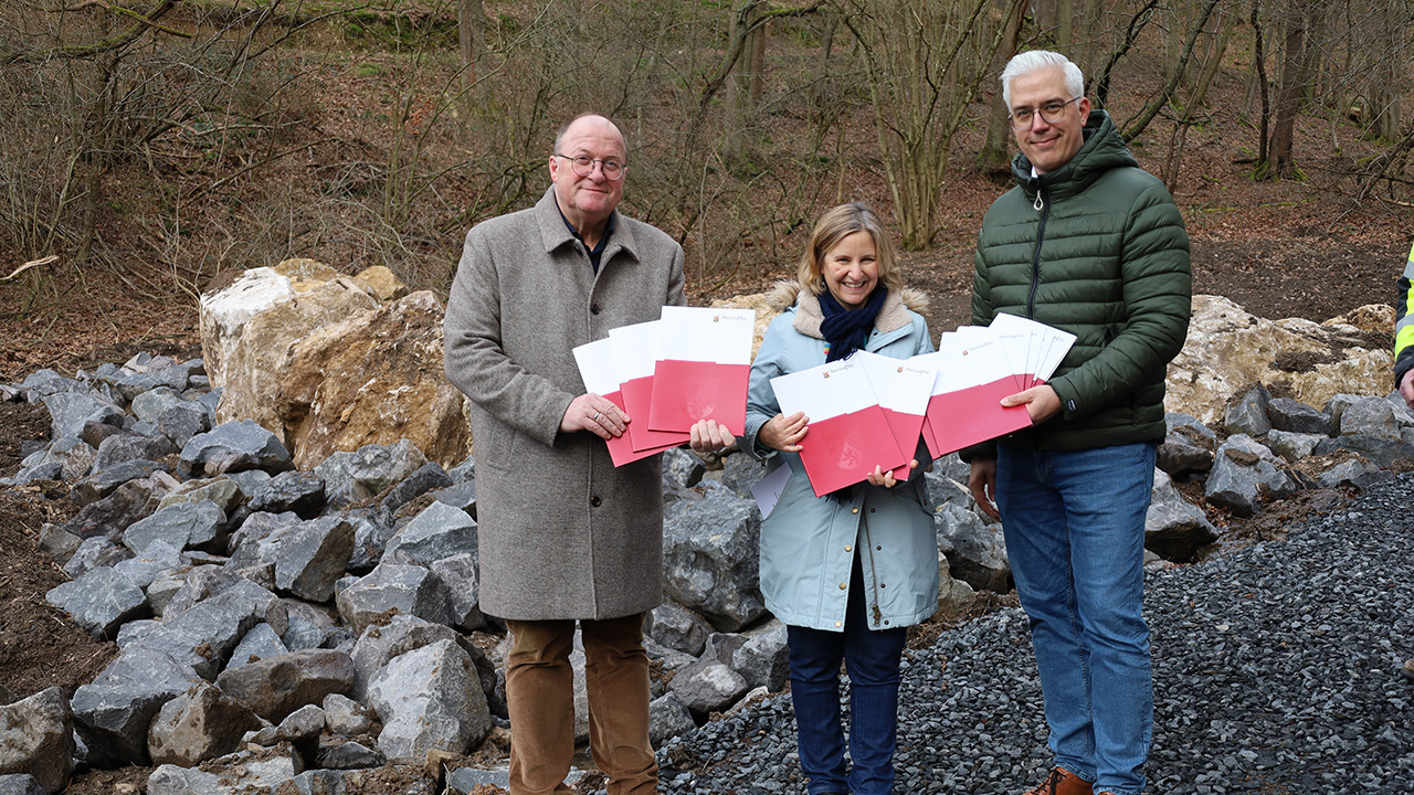 Klimaschutzministerin Katrin Eder übergibt die Förderbescheide an VG-Bürgermeister Guido Nisius (links) und Bürgermeister Dominik Gieler (rechts)