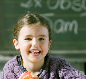 Lachende Schülerin mit einem Apfel in der Hand. Foto: www.5amTag.de