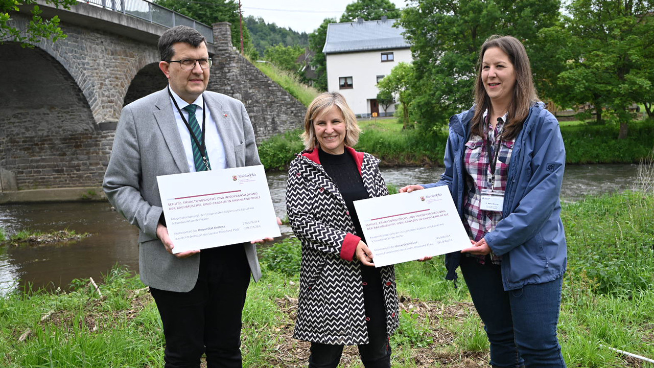 Klimaschutzministerin Katrin Eder übergibt die Förderbescheide an Stefan Wehner, Präsident der Universität Koblenz, und an Meike Köster von der Universität Kassel 