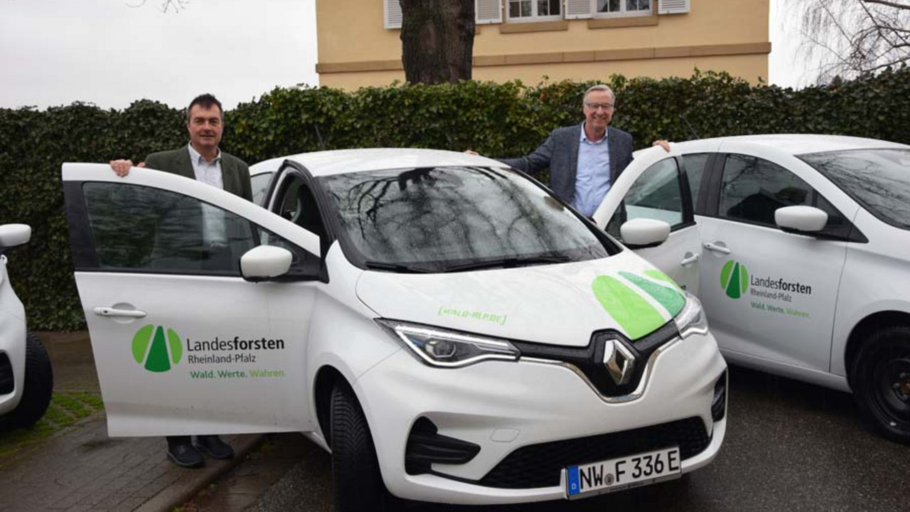 Staatssekretär Thomas Griese und Stefan Asam, Direktor der Zentralstelle der Forstverwaltung, stehen an einem E-Auto