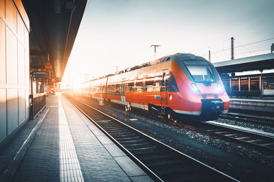 Roter Personenzug fährt schnell durch einen Bahnhof
