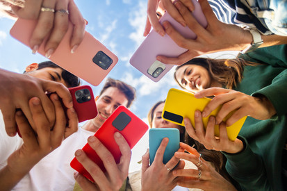 Menschen mit bunten Smartphones stehen im Kreis, von unten Richtung Himmel fotografiert