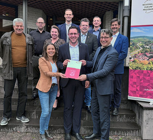 Klimaschutzstaatssekretär Michael Hauer übergibt den Förderbescheid an Marcus Konrad, Bürgermeister der Verbandsgemeinde Speicher