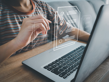 Mensch mit Laptop auf Tisch nutzt virtuelle Formulare