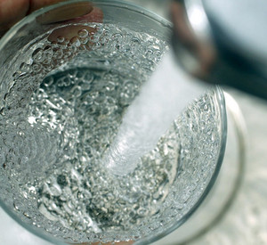 Frisches Wasser fließt aus einem Wasserhahn in ein Glas