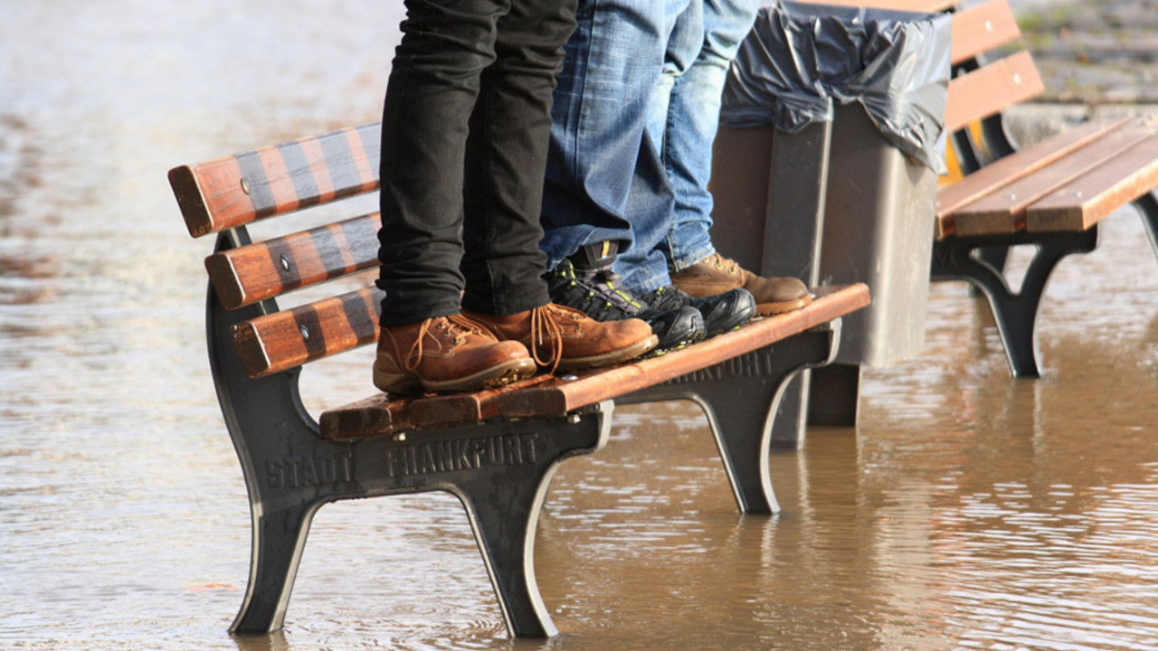 Menschen stehen bei Hochwasser auf einer Bank
