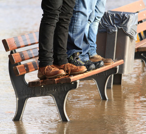 Menschen stehen bei Hochwasser auf einer Bank