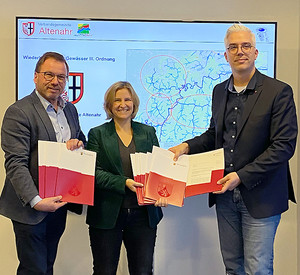 Im Beisein von SGD-Nord Präsident Wolfgang Treis übergibt Klimaschutzministerin Katrin Eder VG-Bürgermeister Dominik Gieler die Förderbescheide.