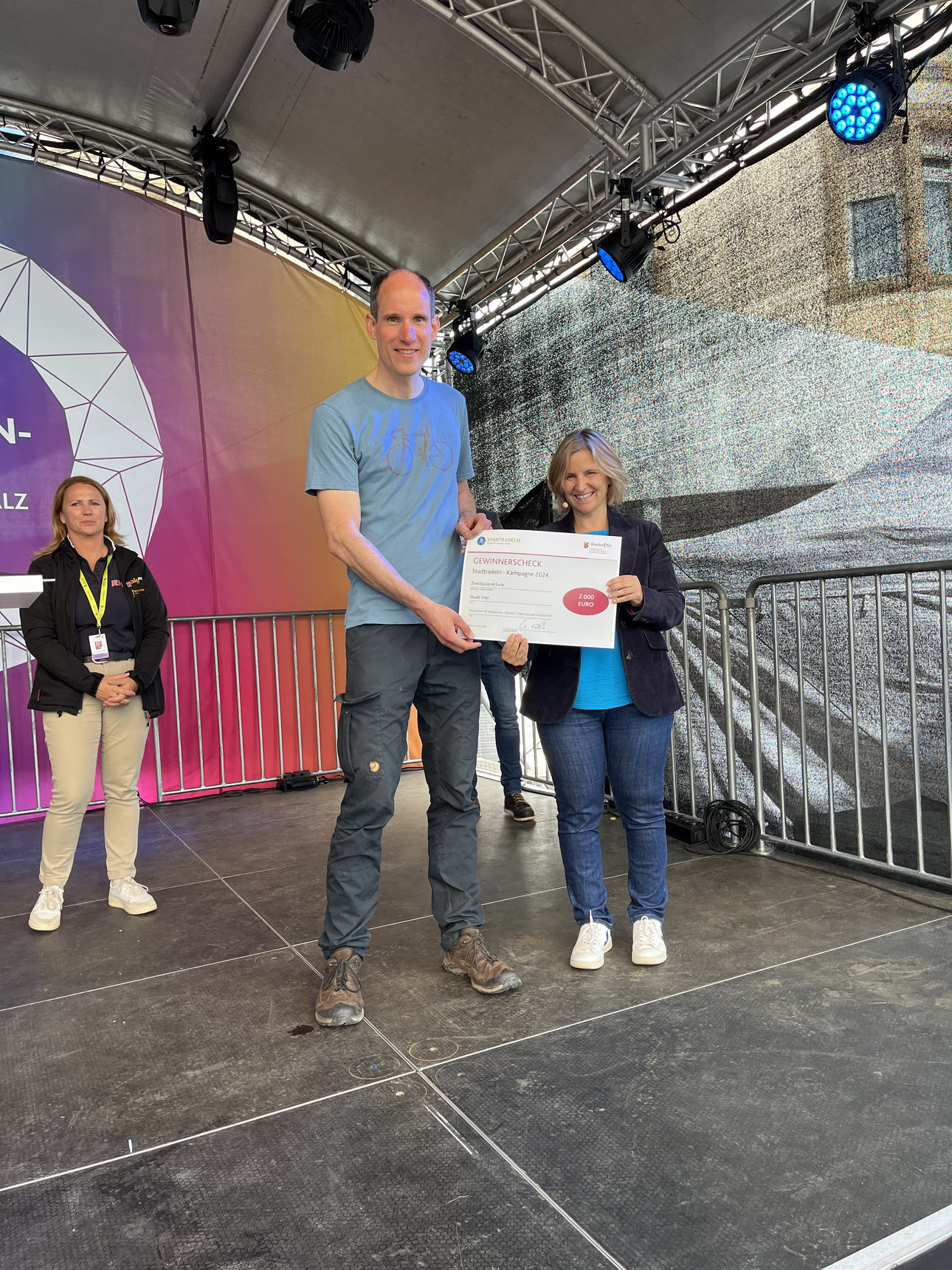 Mobilitätsministerin Katrin Eder überreicht der Vertreter der Stadt Trier den Gewinnerscheck für die erfolgreiche Teilnahme am Stadtradeln-Wettbewerb 2024