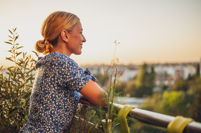 Frau genießt Ausblick von ihrem Balkon