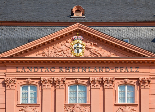 Ein rotes Gebäude mit schwarzen Ziegeln. Das Gebäude hat drei Fenster über denen "Landtag Rheinland-Pfalz" steht.  