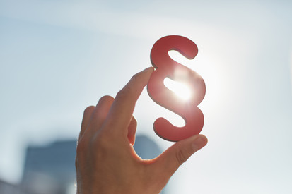 Hand hält Paragraphen in die Sonne als Zeichen für Recht und Gerechtigkeit