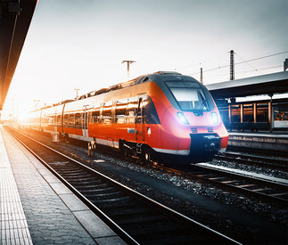 Roter Personenzug fährt schnell durch einen Bahnhof